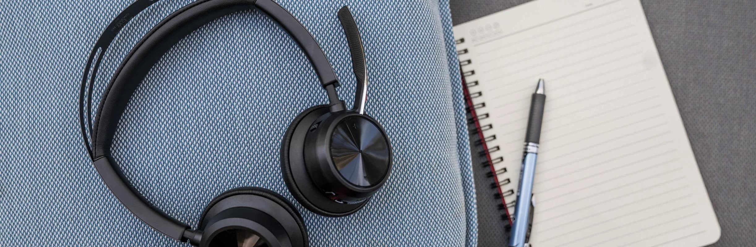 Poly Voyager Focus 2 headset resting on an office chair beside a notebook